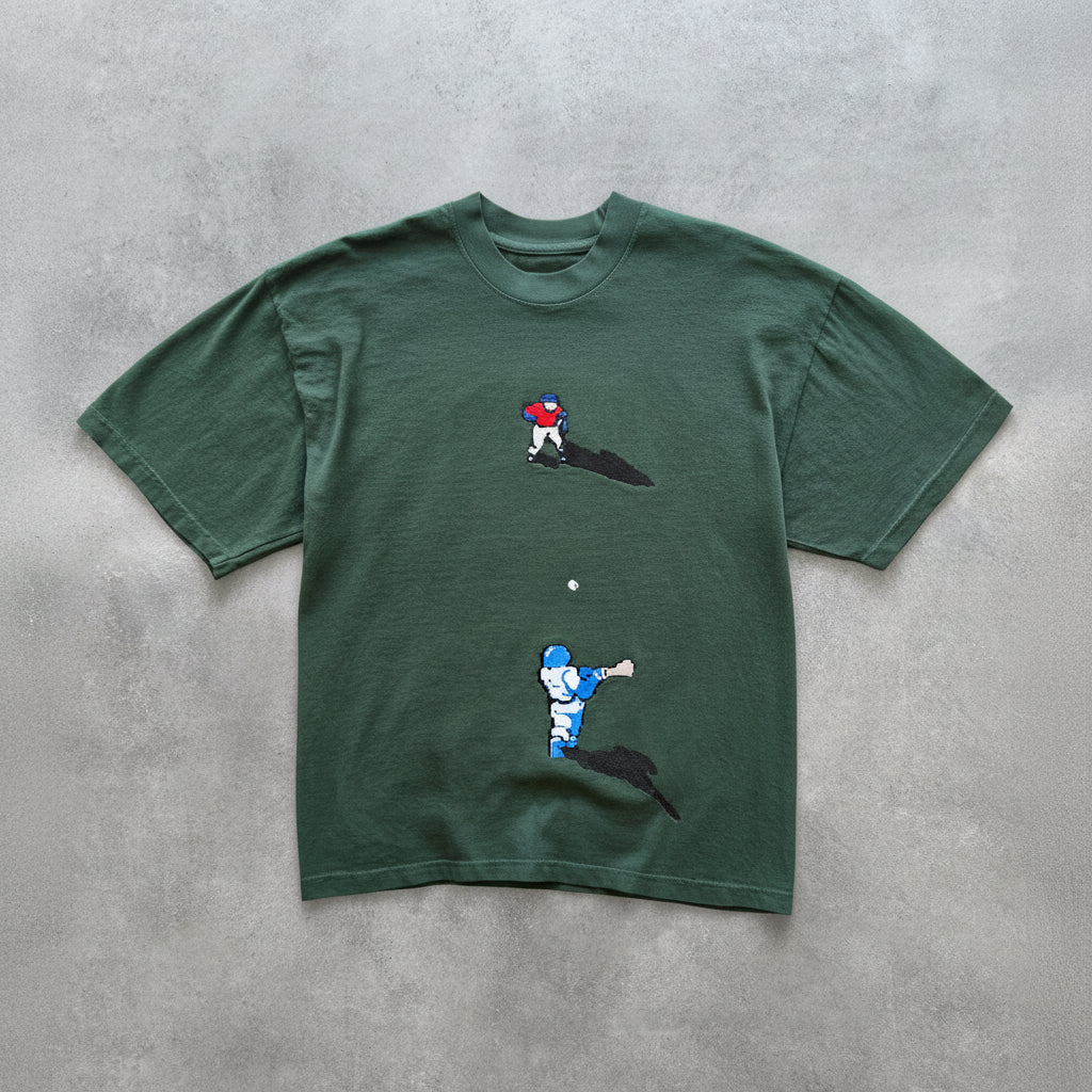 Green t-shirt with pixelated graphics of a baseball player on a grey surface