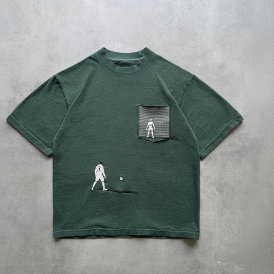 Green t-shirt with pocket and graphic design on a grey surface