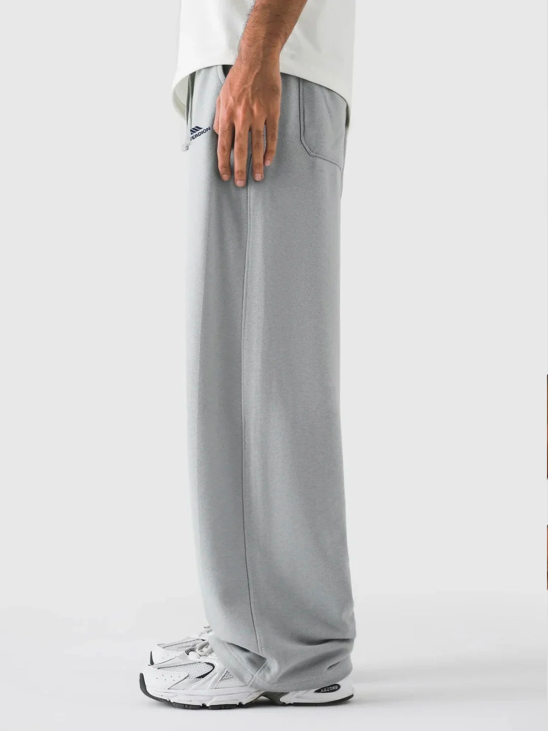Person wearing grey pants and white sneakers on a white background