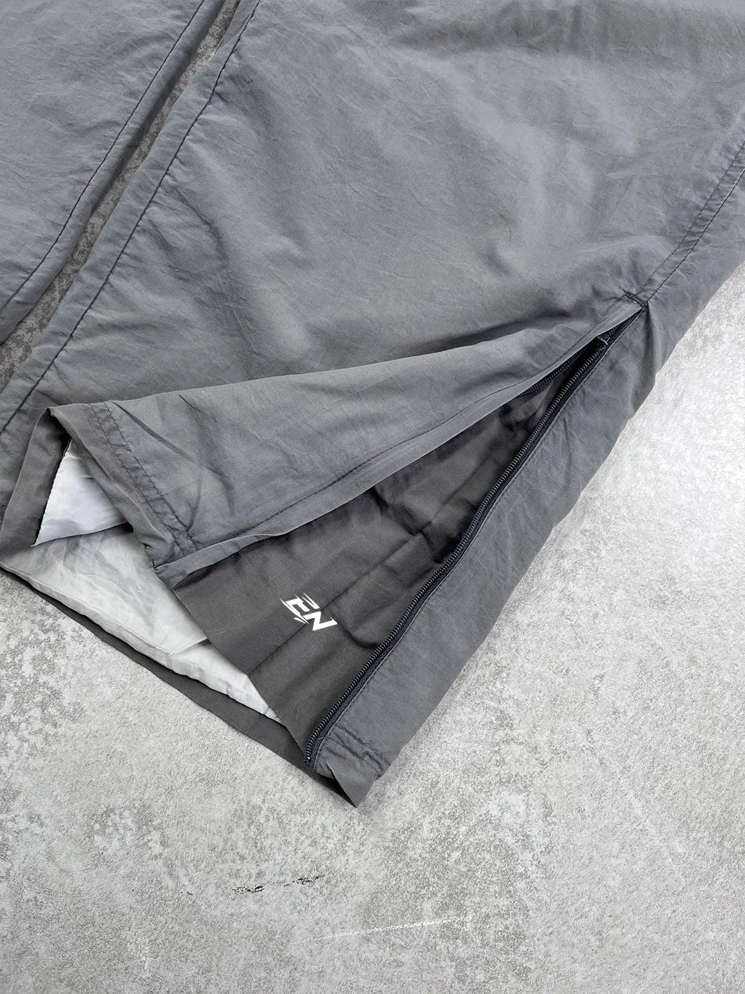 Grey pants with a brand logo on a concrete surface