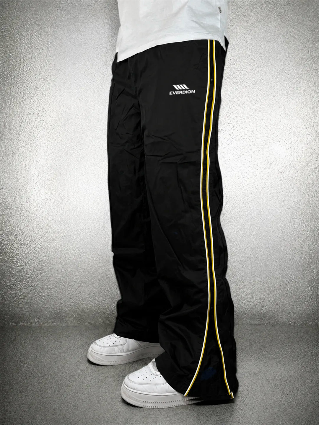 Black track pants with a red stripe and brand logo on a grey background