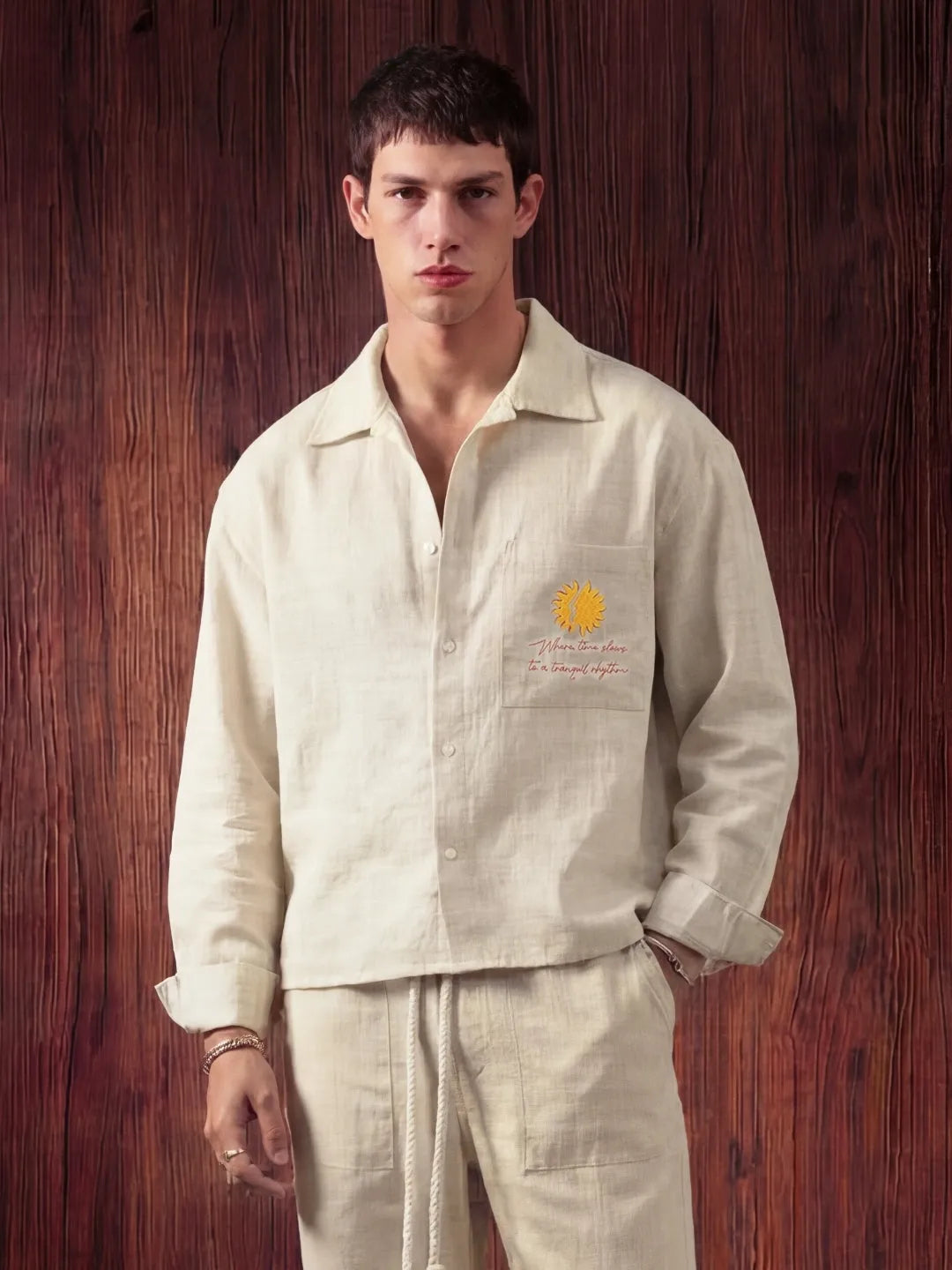 Man wearing a white shirt with a logo against a wooden background