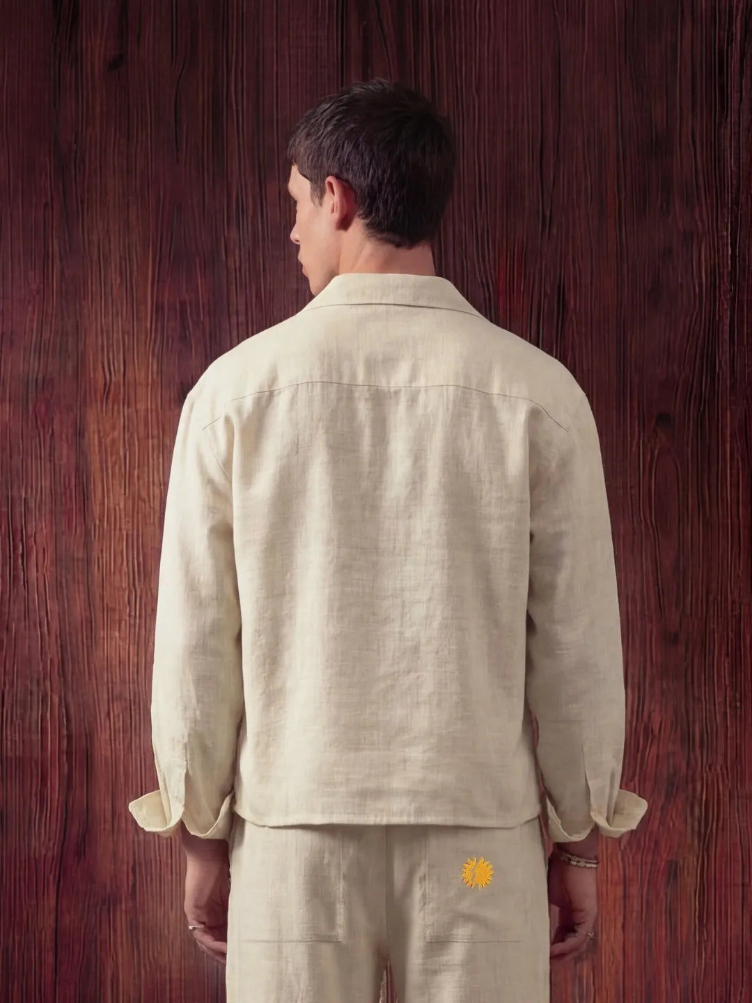 Man wearing a beige outfit with a logo on a wooden background