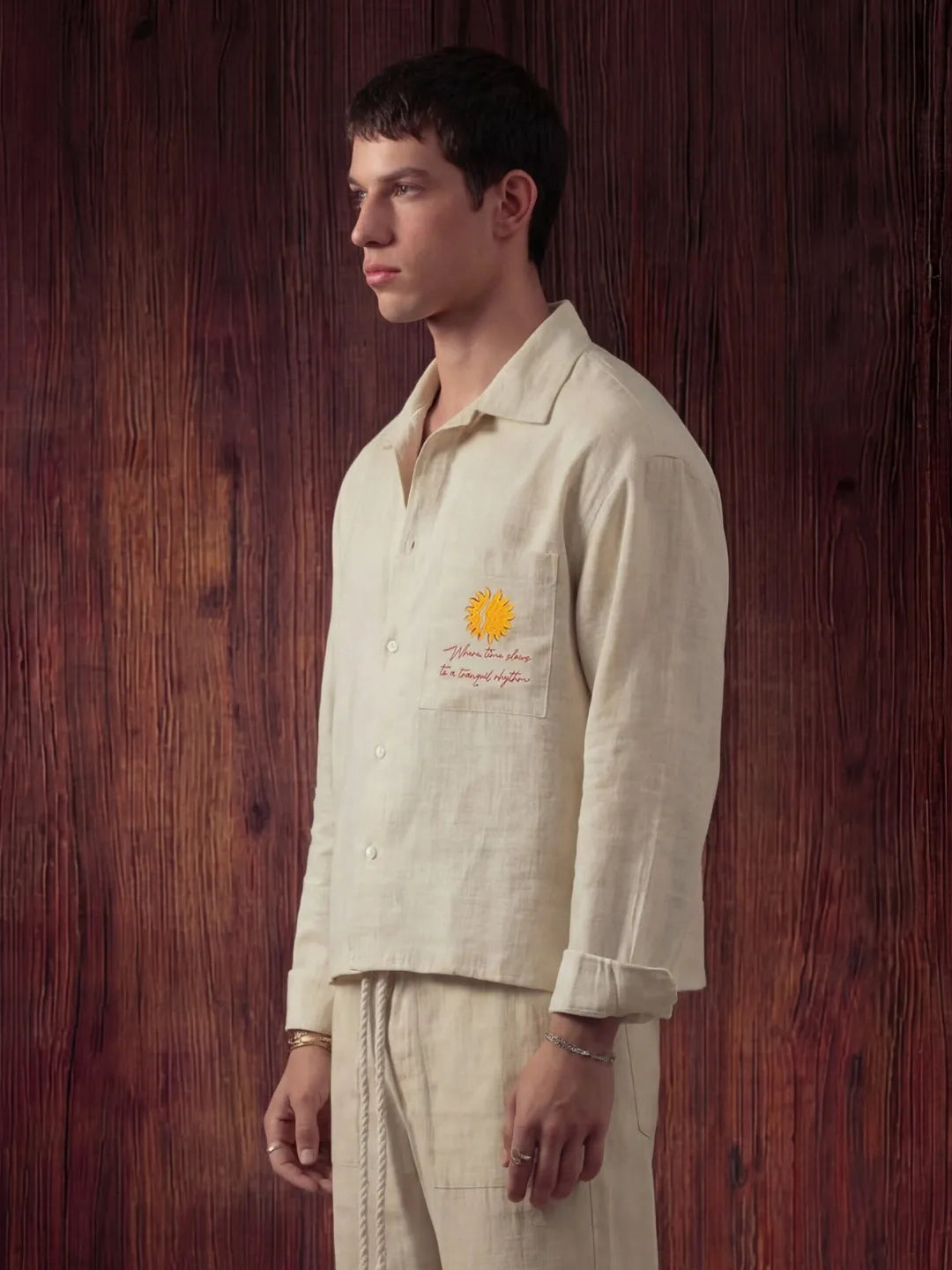 Man wearing a light-colored shirt with a logo against a wooden background