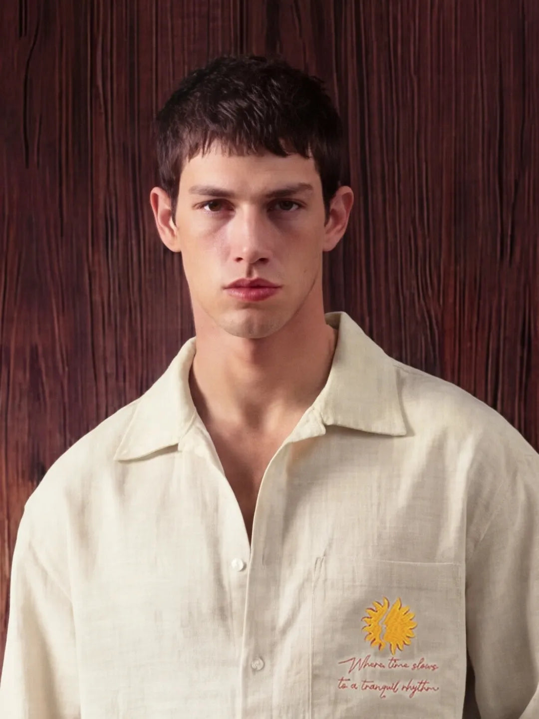 Man wearing a light-colored shirt with a sunflower design against a wooden background