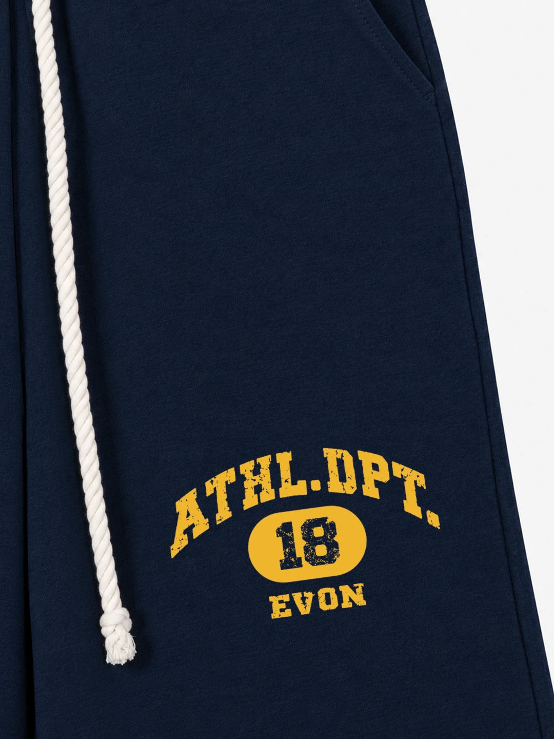 Close-up of a navy blue sweatpant or hoodie showing a white drawstring and yellow collegiate-style text reading 'ATHL.DPT.