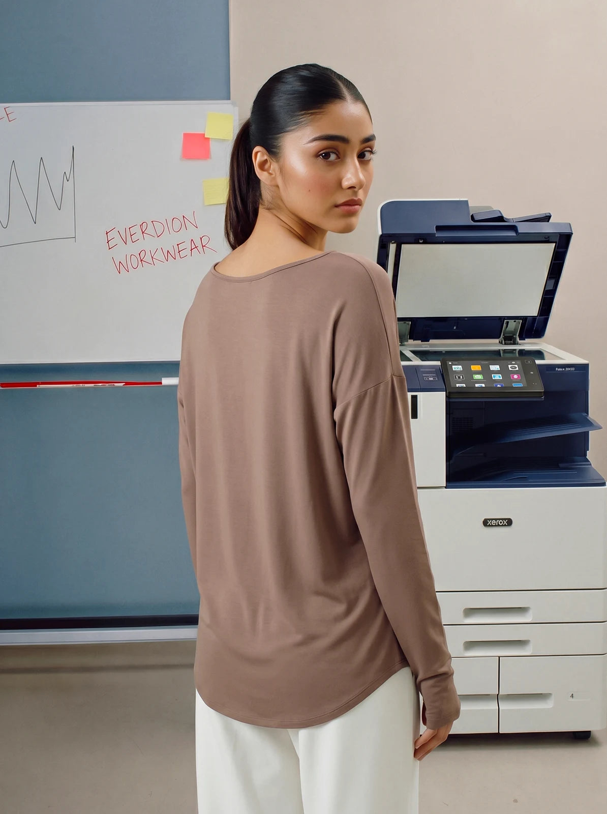 Woman wearing a brown long-sleeve top in an office setting