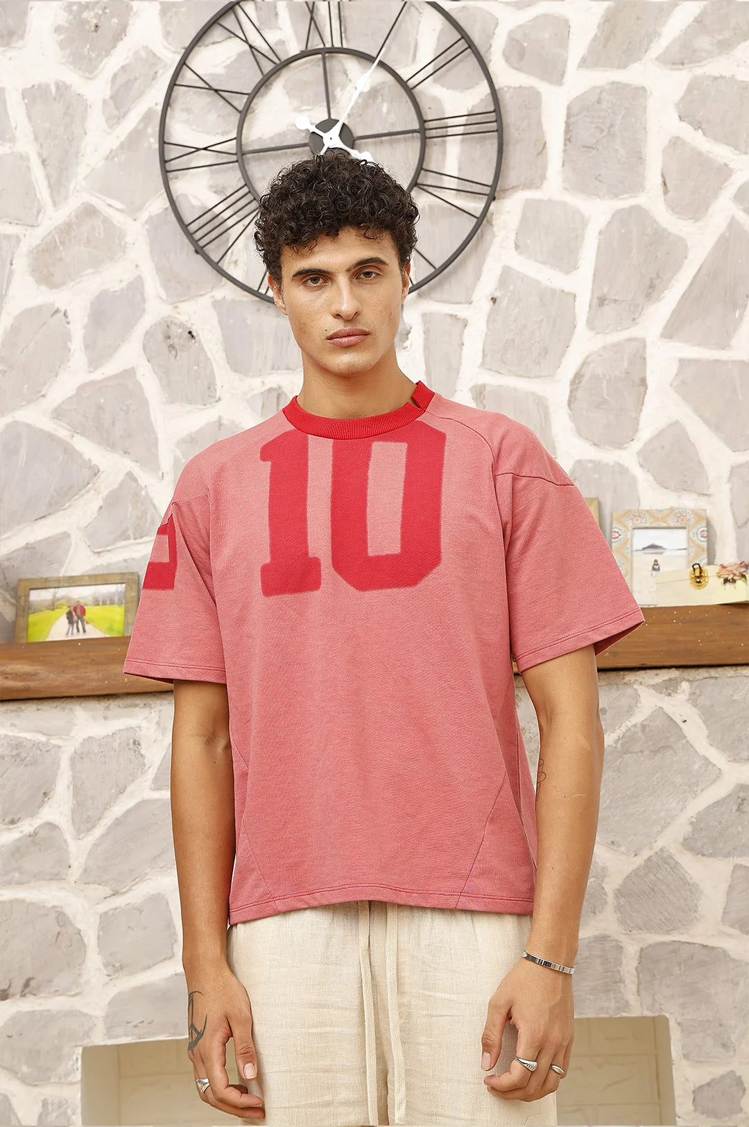 Person wearing a red t-shirt with number 10 design against a stone wall background