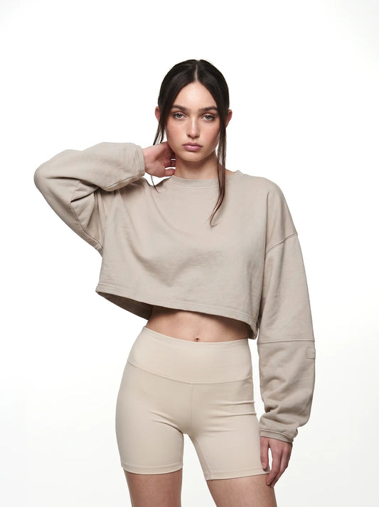 Woman wearing a beige cropped t-shirt and shorts on a white background