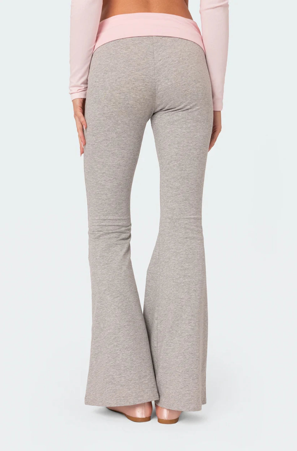 Grey flared pants worn by a person on a white background