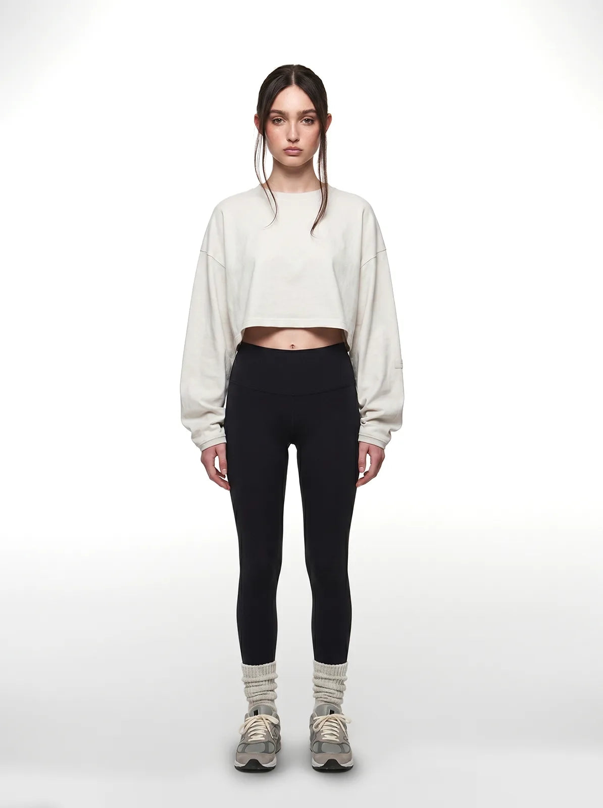 Person wearing a white cropped t-shirt and black leggings on a white background