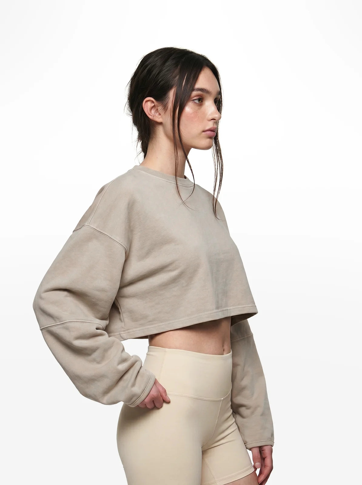 Woman wearing a beige cropped t-shirt and leggings on a white background