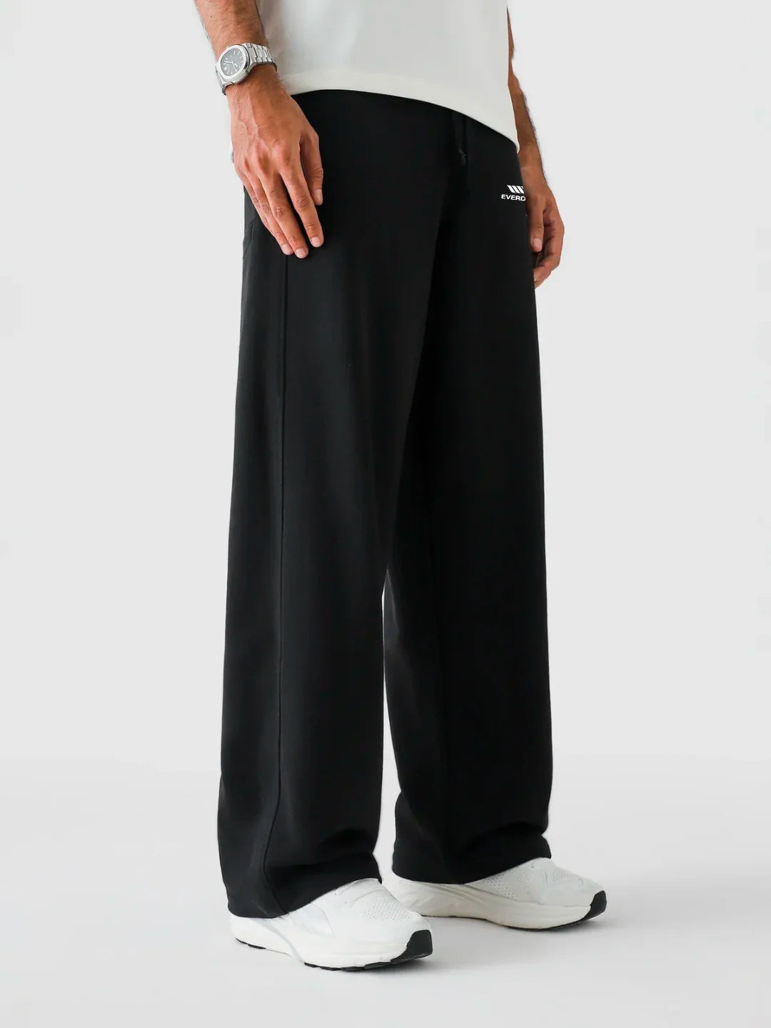 Person wearing black pants with a brand logo on a white background
