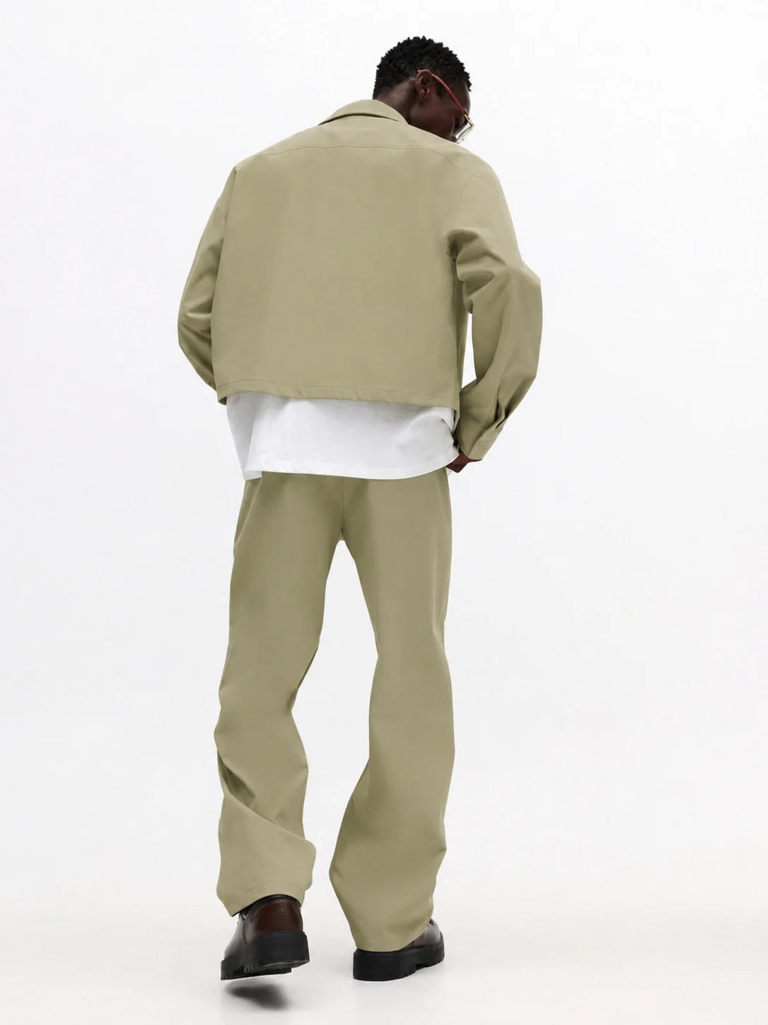 Person wearing a beige jacket and pants on a white background