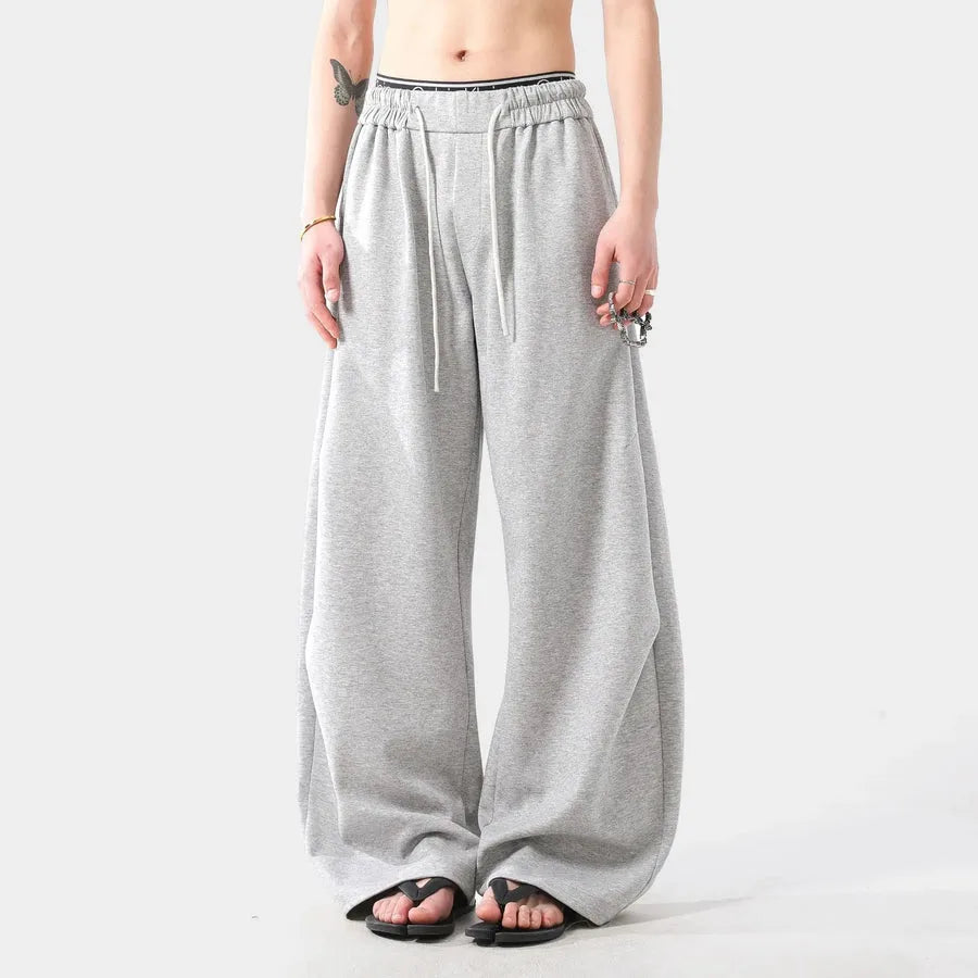 Person wearing grey wide-leg sweatpants on a white background