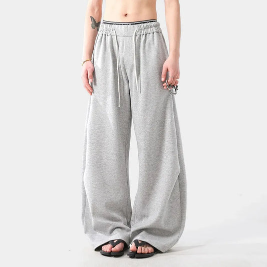 Person wearing grey wide-leg sweatpants on a white background