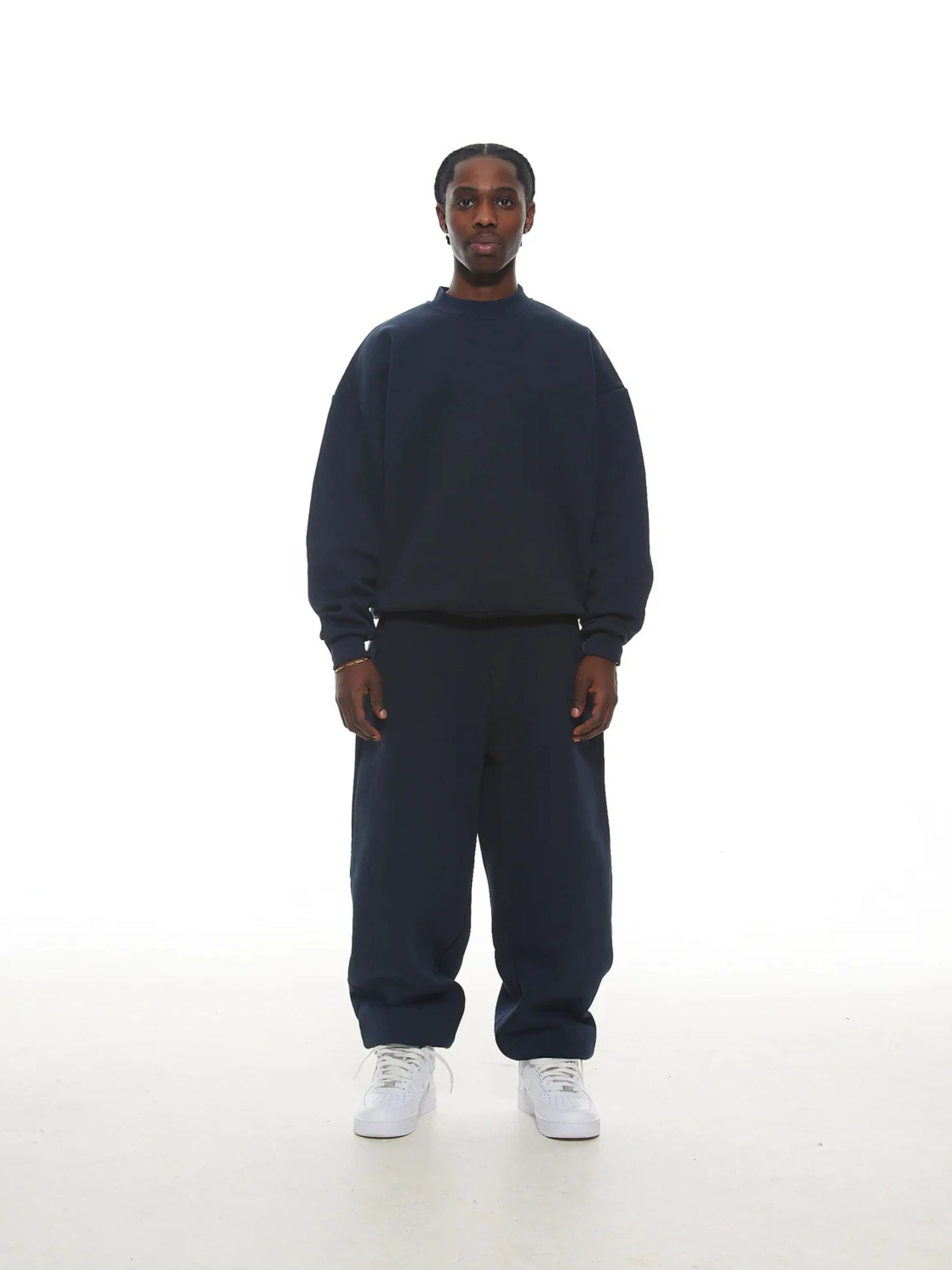 Person wearing a navy blue sweatshirt and sweatpants set on a white background