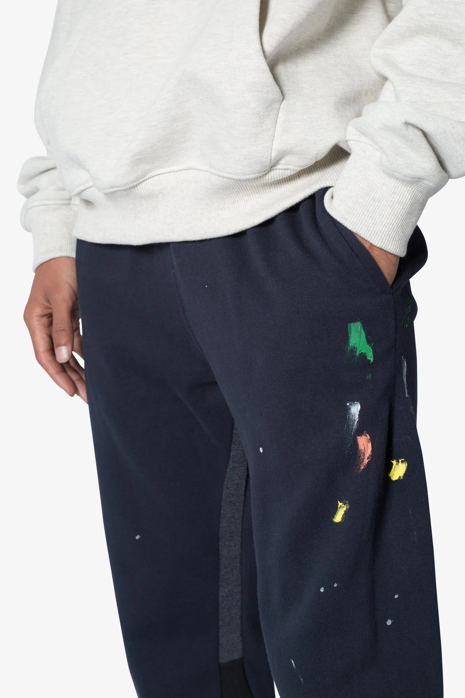 Navy blue pants with colorful patches worn by a person on a white background