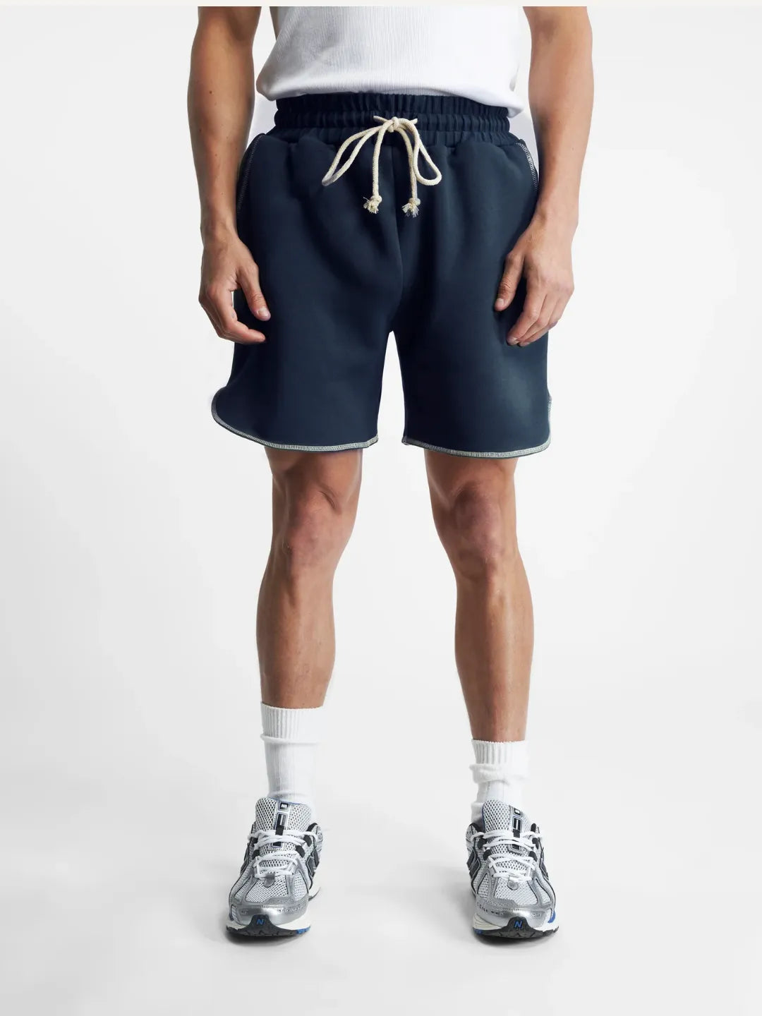 Person wearing navy running shorts with a white background