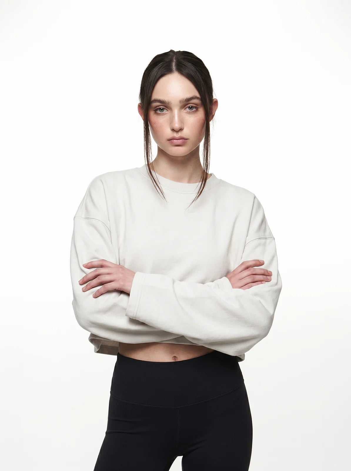 Woman wearing a white cropped t-shirt and black pants on a white background