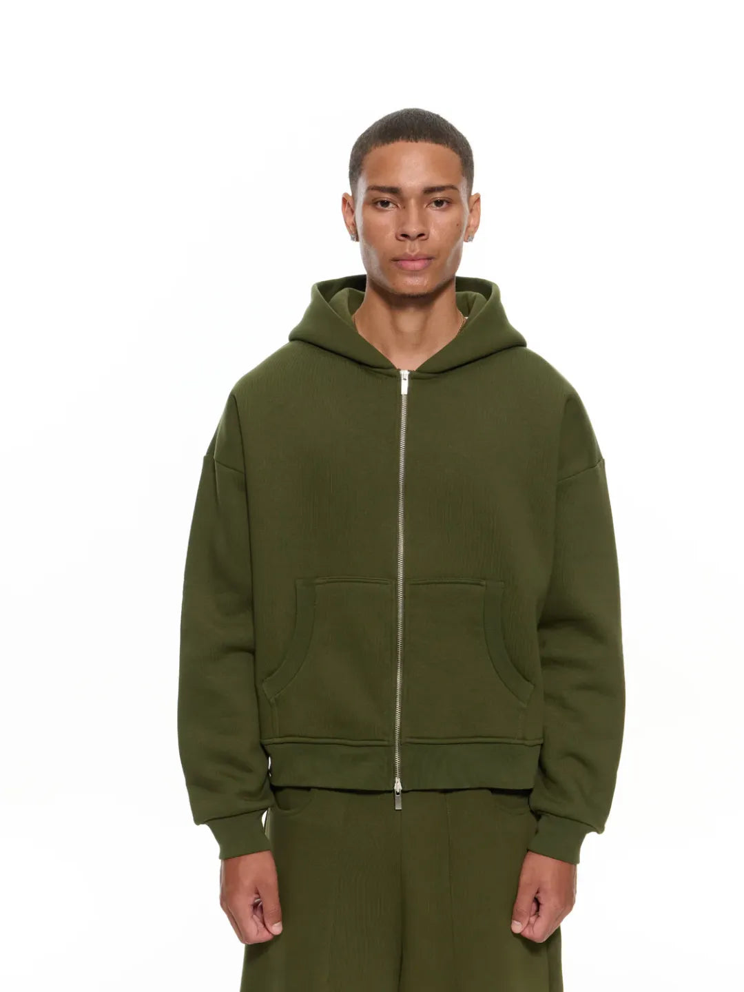 Person wearing an olive green zip-up jacket on a white background