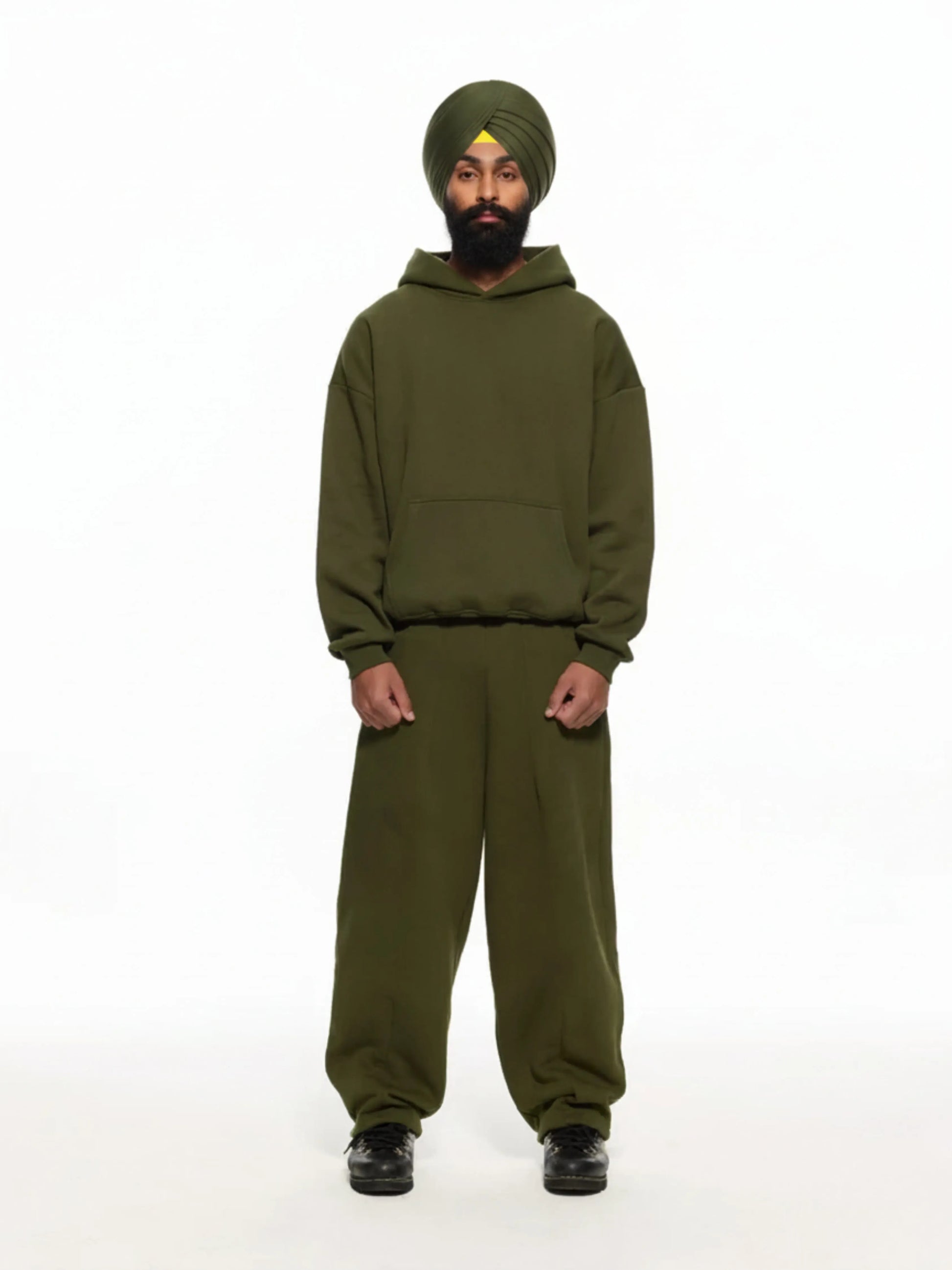 Person wearing a green tracksuit and turban on a white background