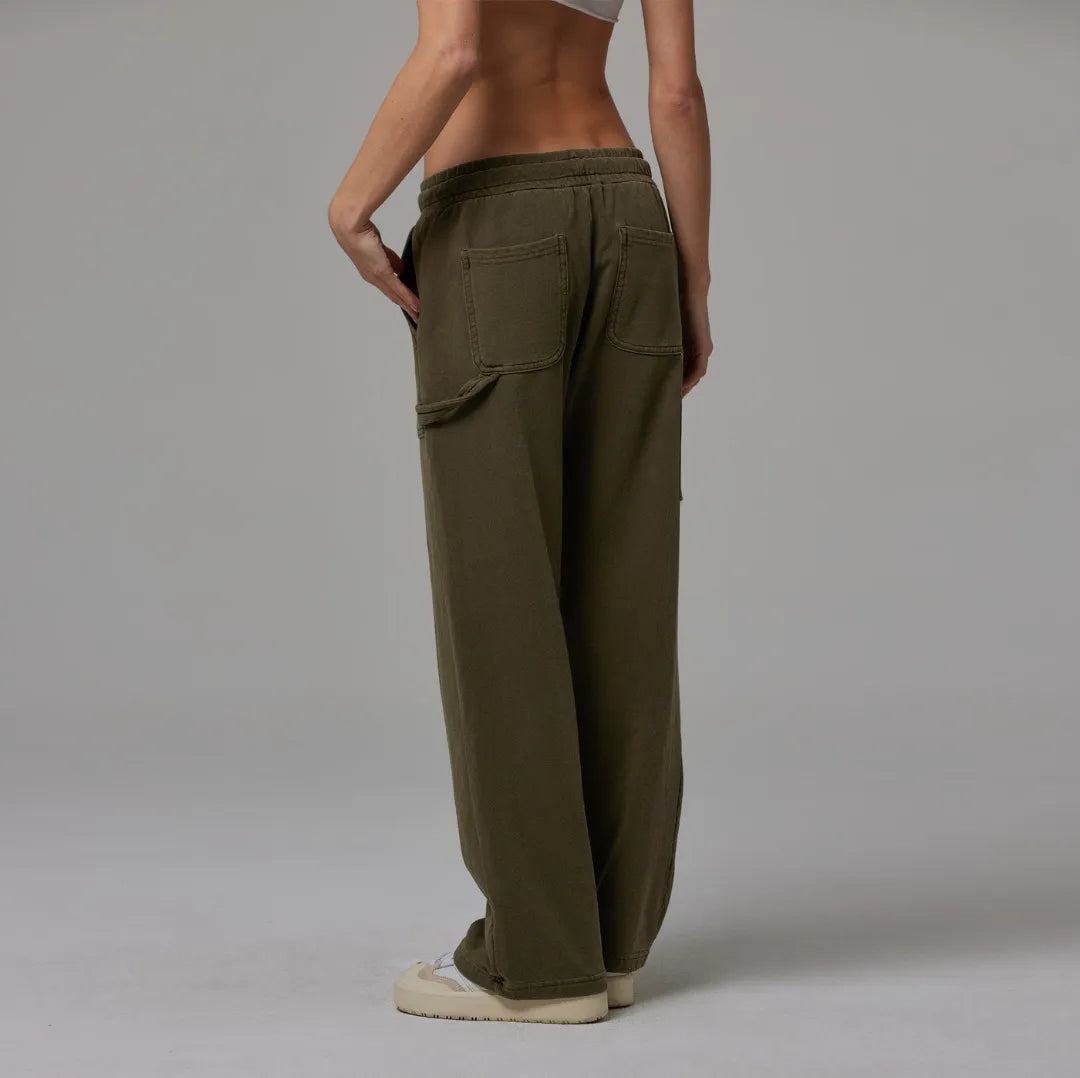 Person wearing olive drawstring sweatpant on a plain background
