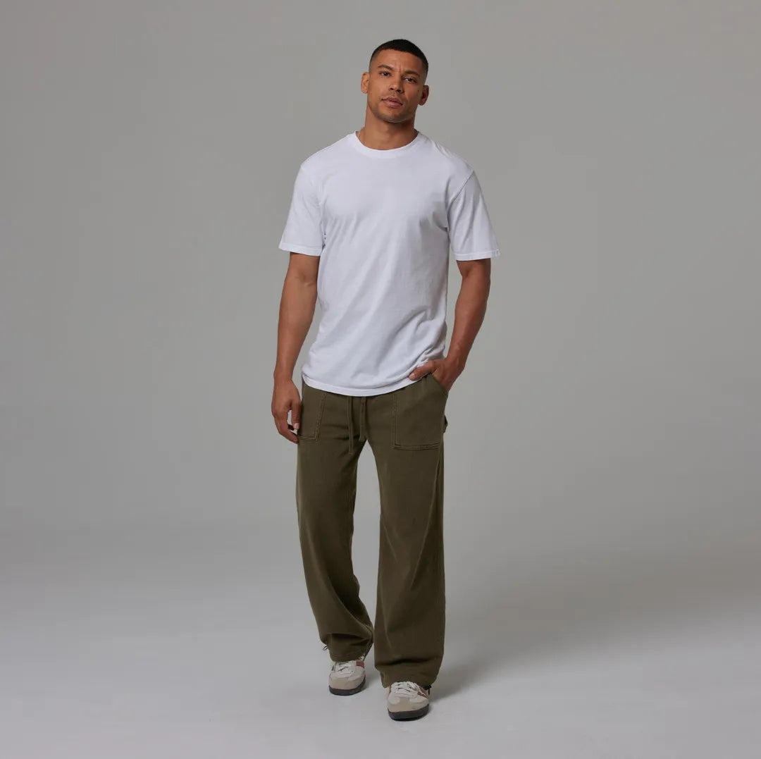 Man wearing a white t-shirt and olive sweatpants against a grey background