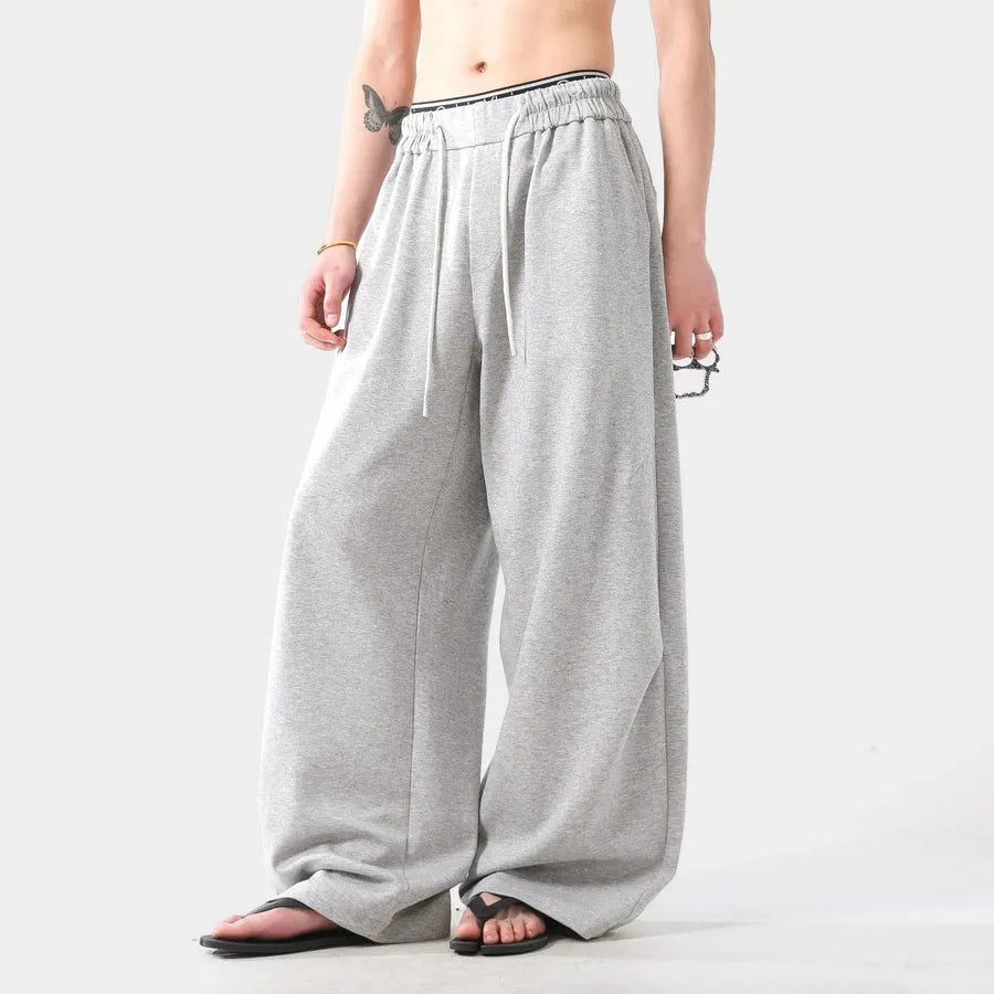 Person wearing grey wide-leg pants on a white background