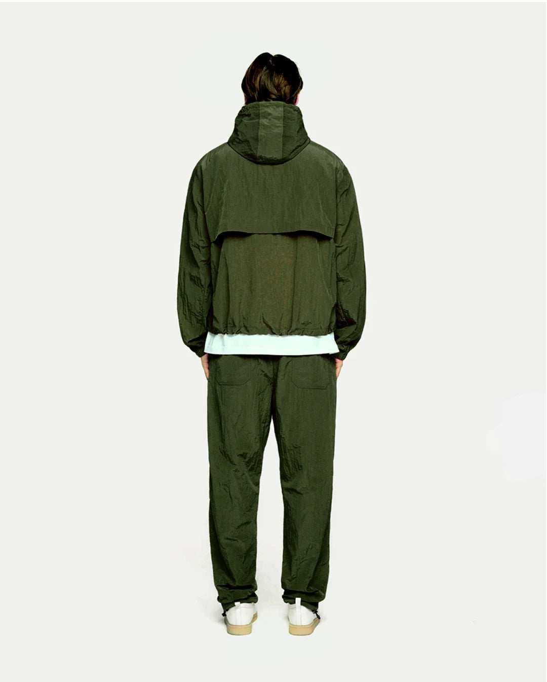 Person wearing a olive raincoat and pants on a white background