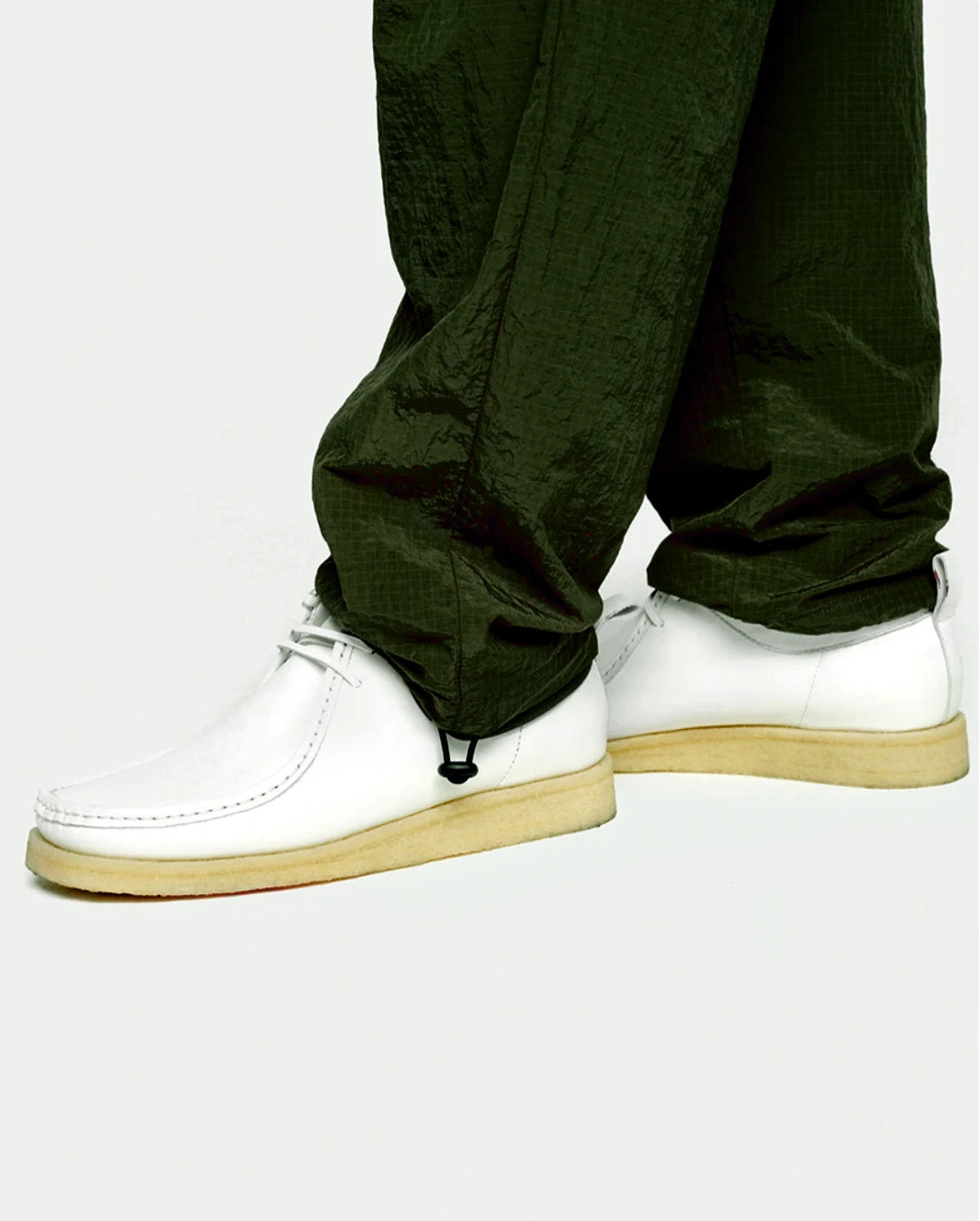 olive pants worn with white sneakers on a plain background
