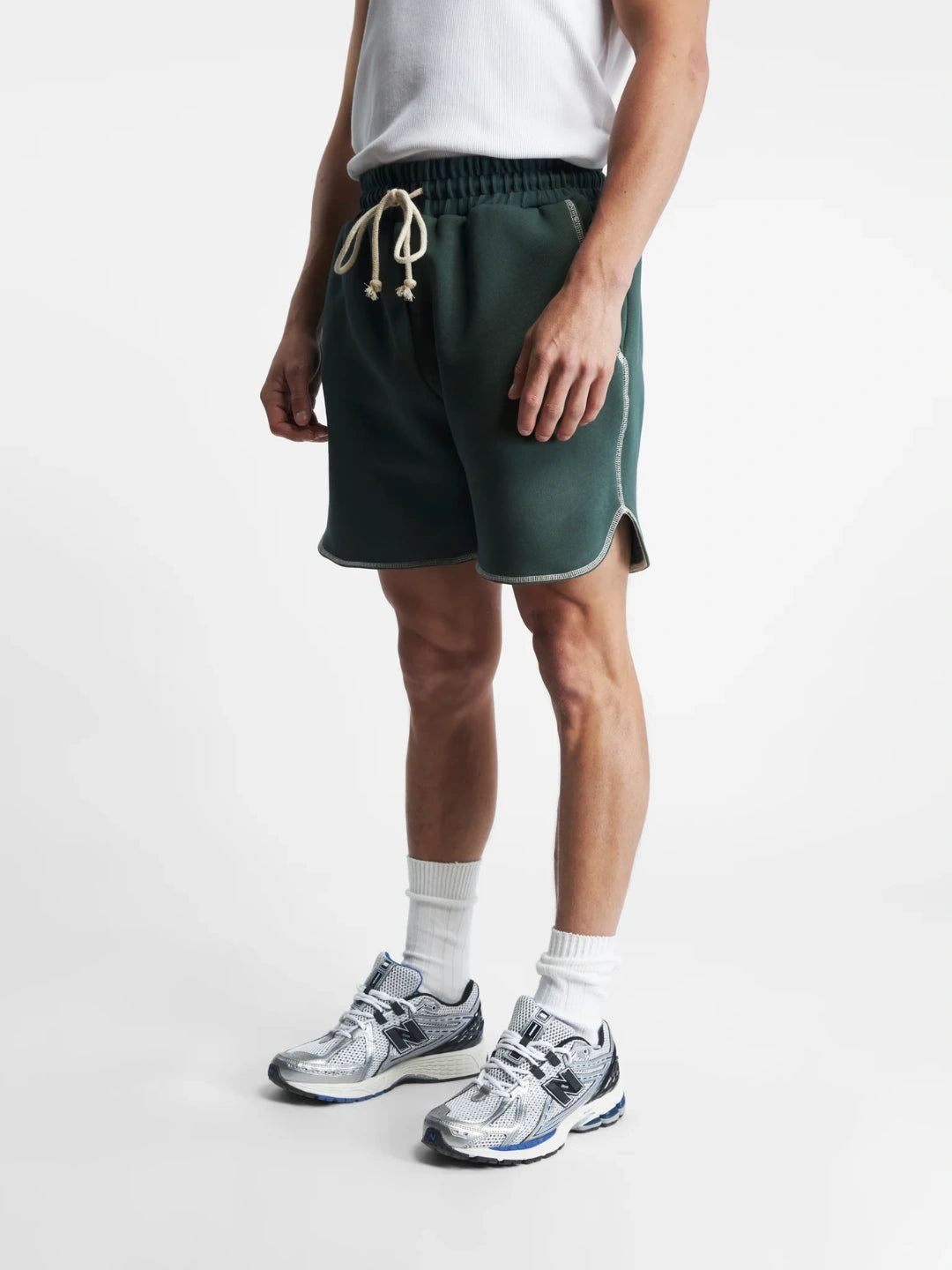 Person wearing green shorts, white socks, and sneakers on a white background