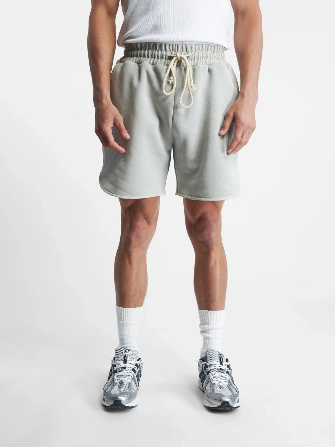 Person wearing light grey shorts on a white background