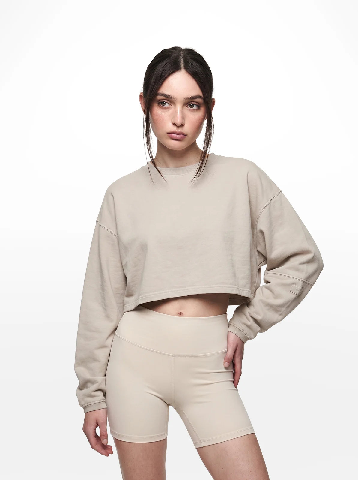 Woman wearing a beige cropped t-shirt and shorts on a white background