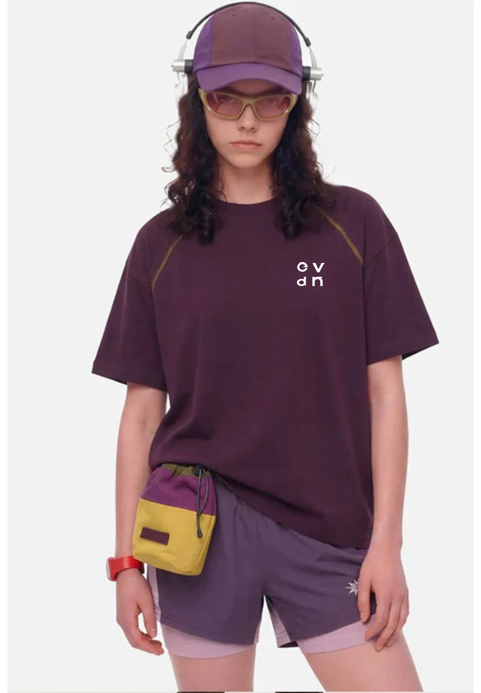 Person wearing a purple t-shirt and shorts with a yellow bag, on a white background