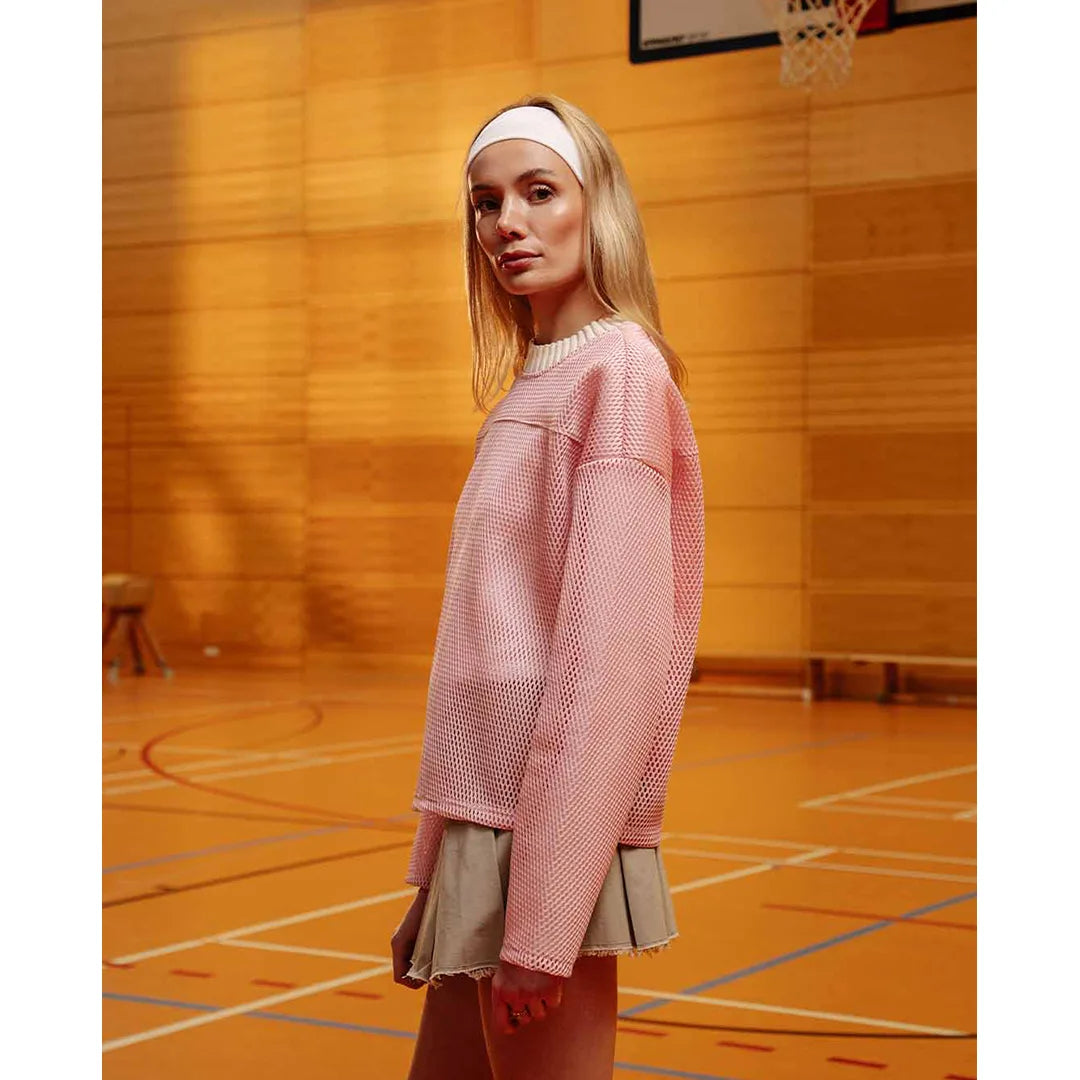 Woman in a pink sweater and skirt standing on a basketball court