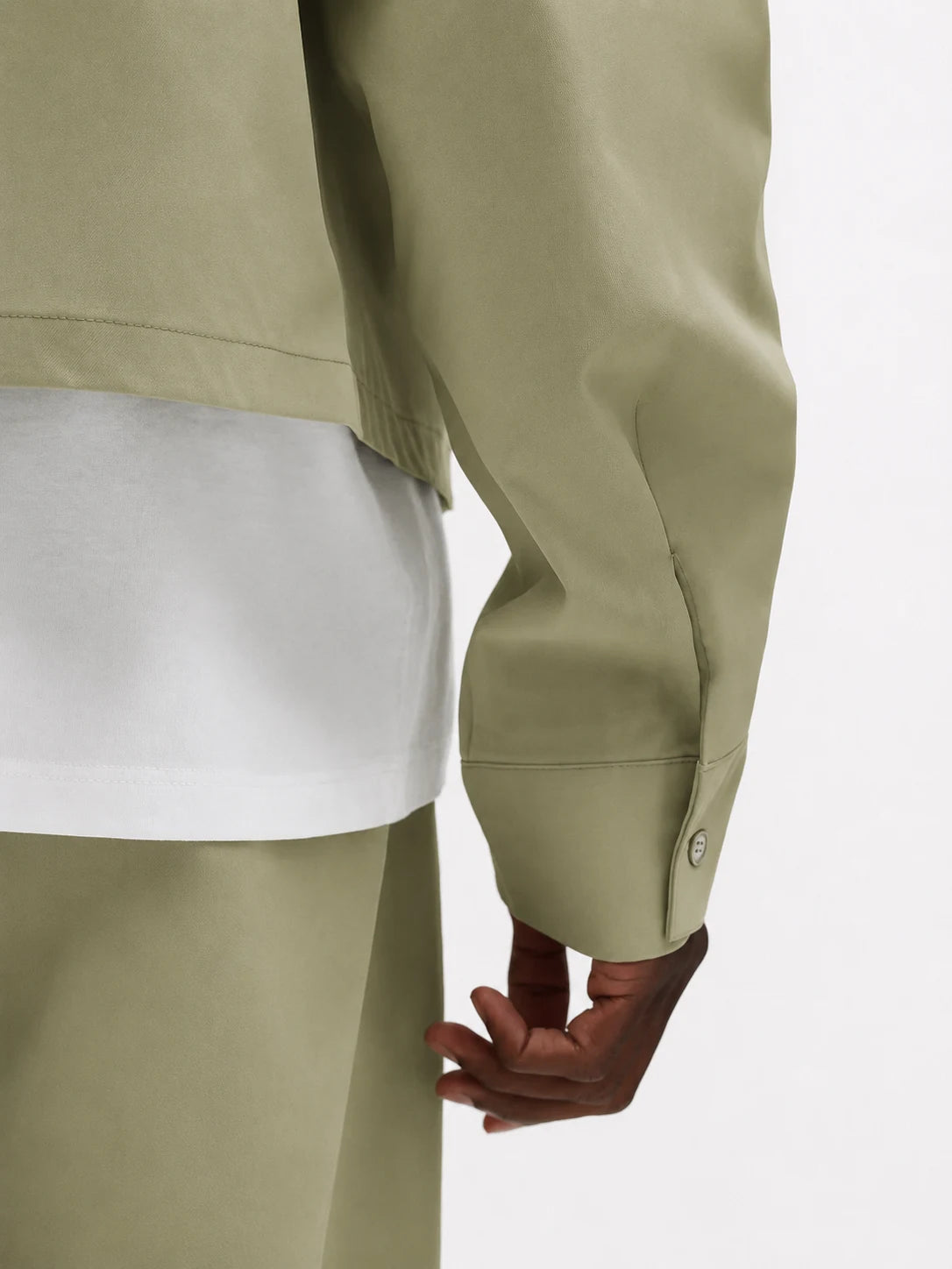 Person wearing a light green jacket and pants on a white background