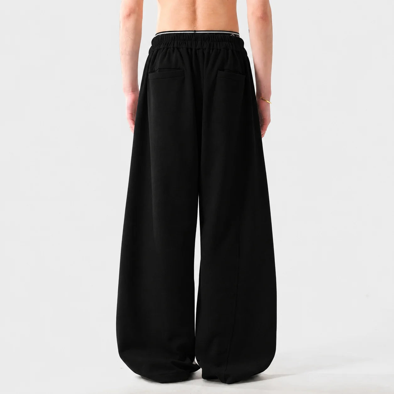 Black wide-leg sweatpants worn by a person on a light grey background
