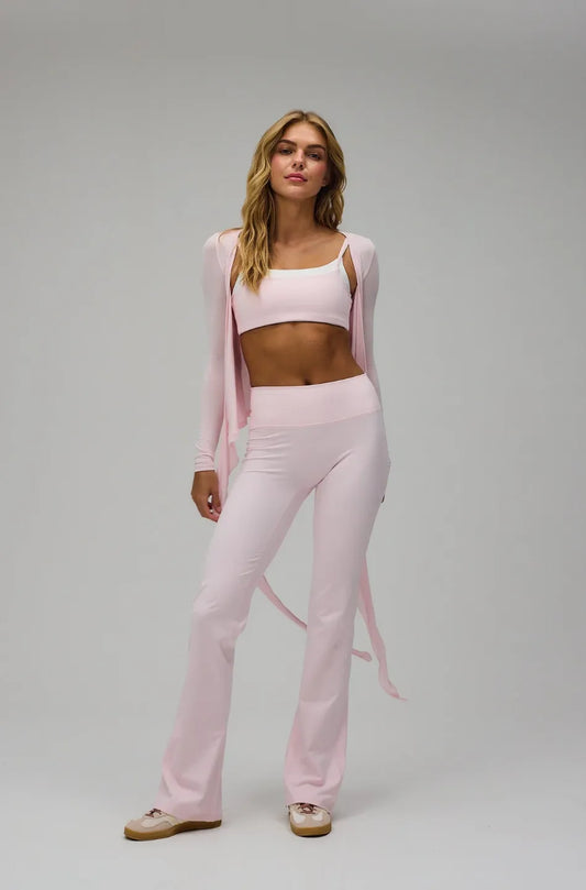 Woman wearing a pink outfit with a cardigan on a grey background