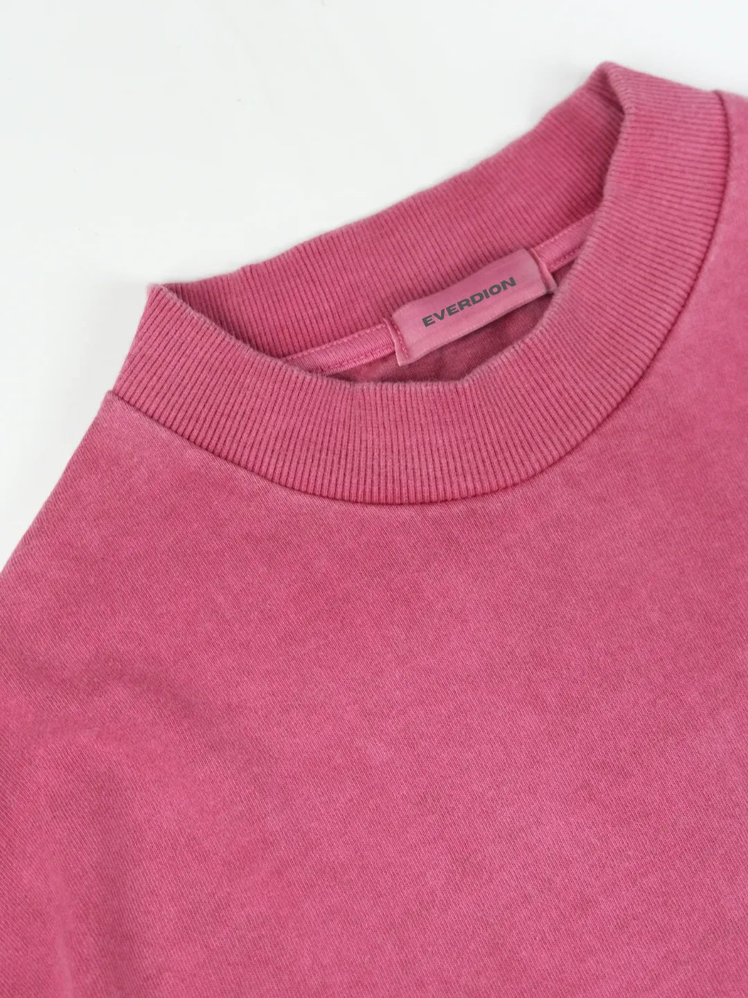 Close-up of a pink t-shirt with a brand label on a white background