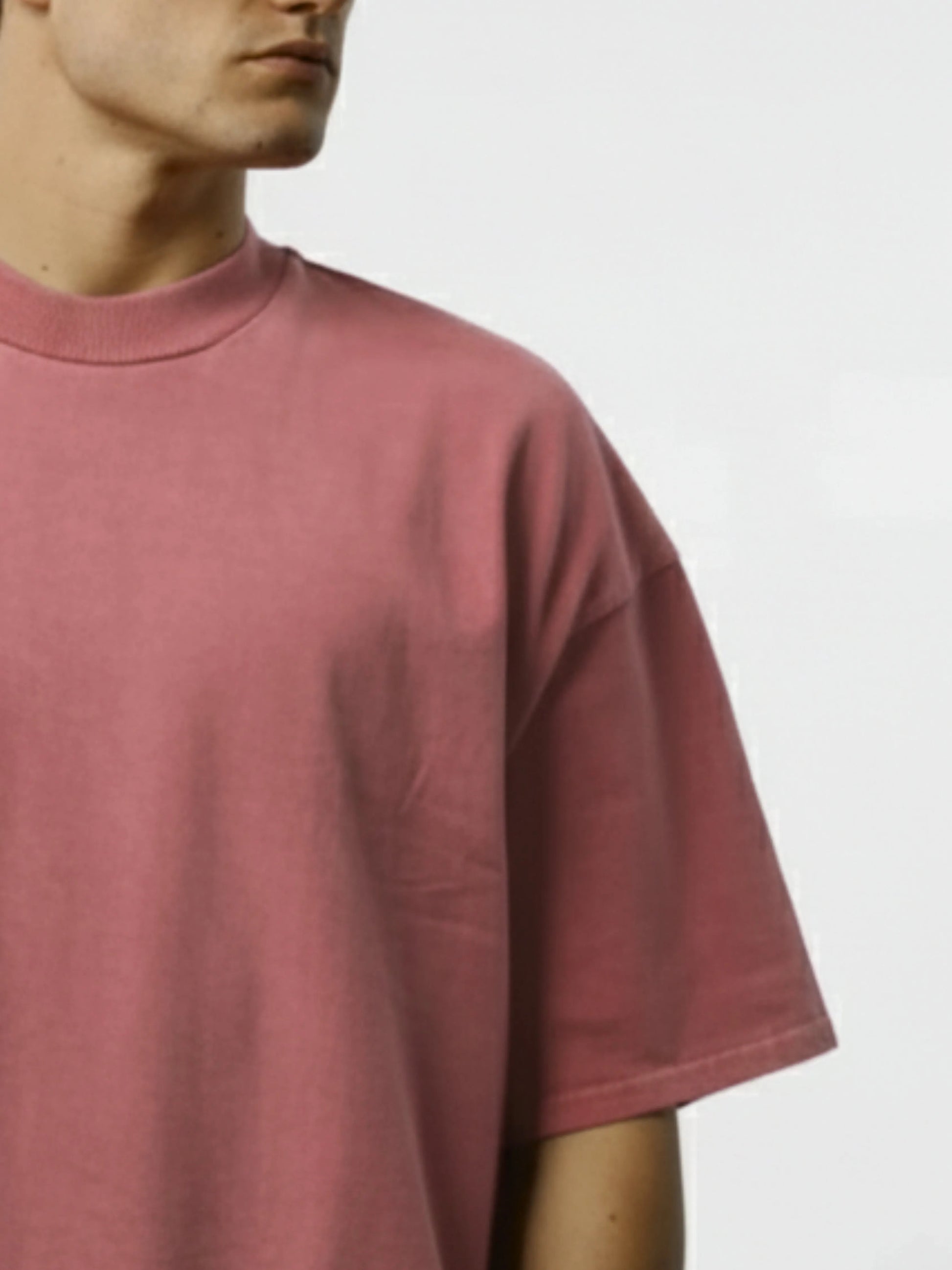 Person wearing a pink t-shirt on a light grey background