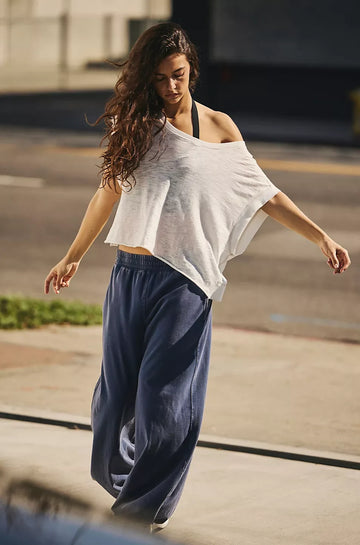 Woman in a white top and blue pants walking outdoors.