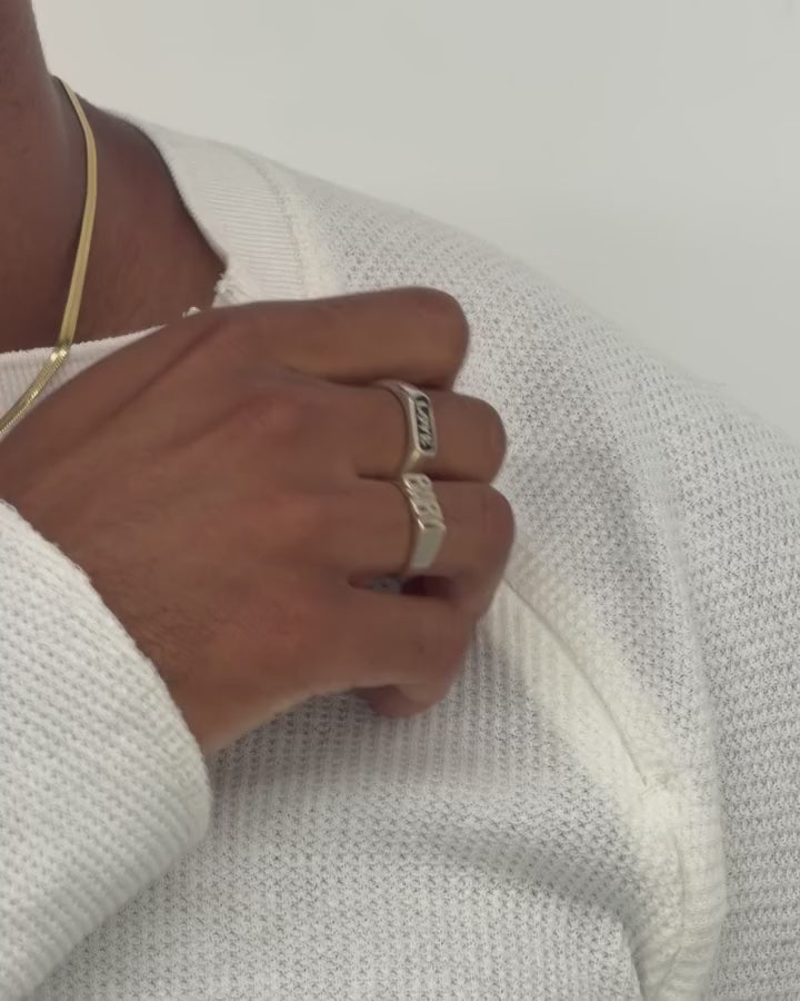 Close-up of a person wearing a white textured knit long-sleeve top against a plain light grey wall.