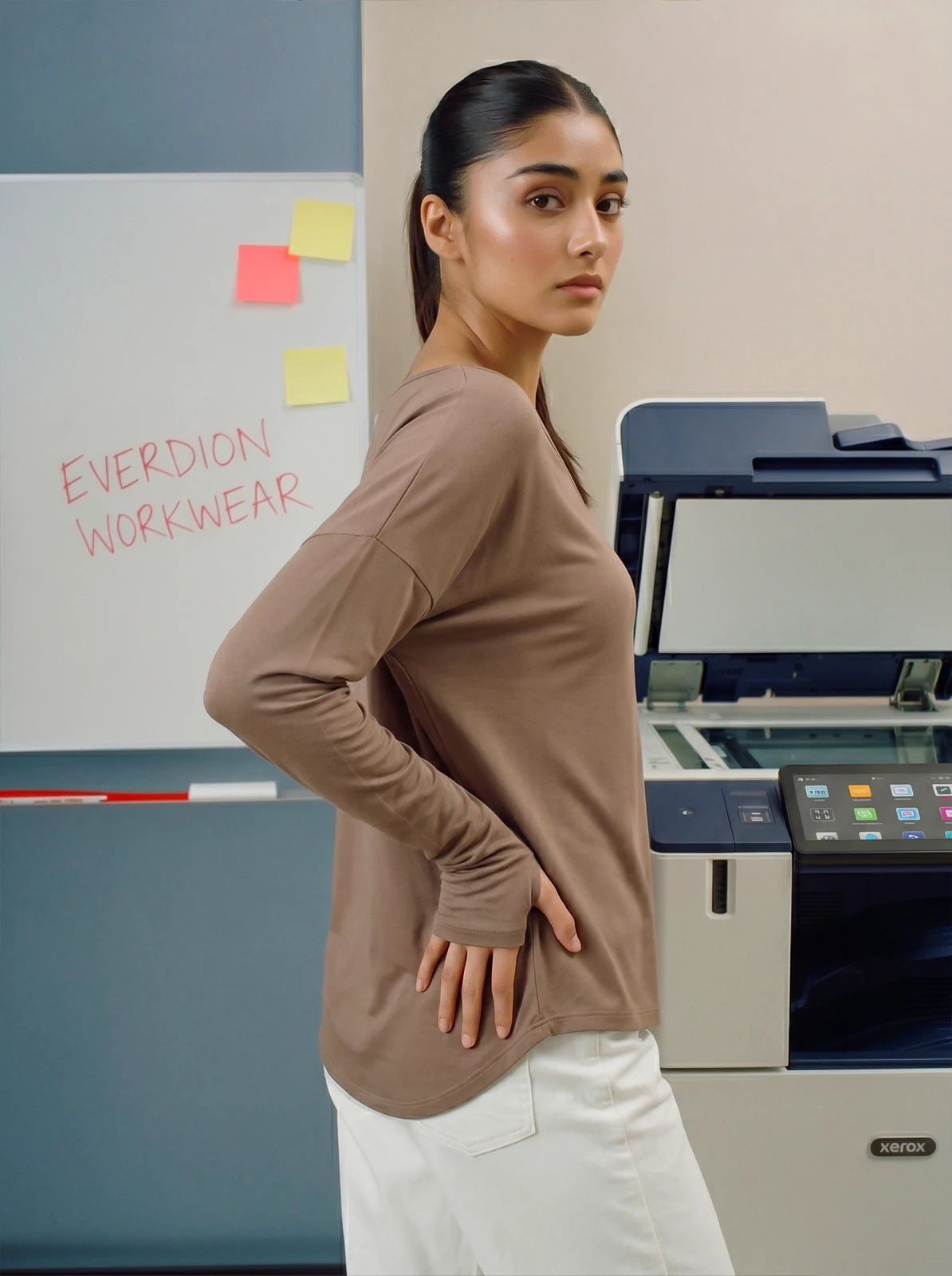 Woman wearing a brown long-sleeve top in an office setting