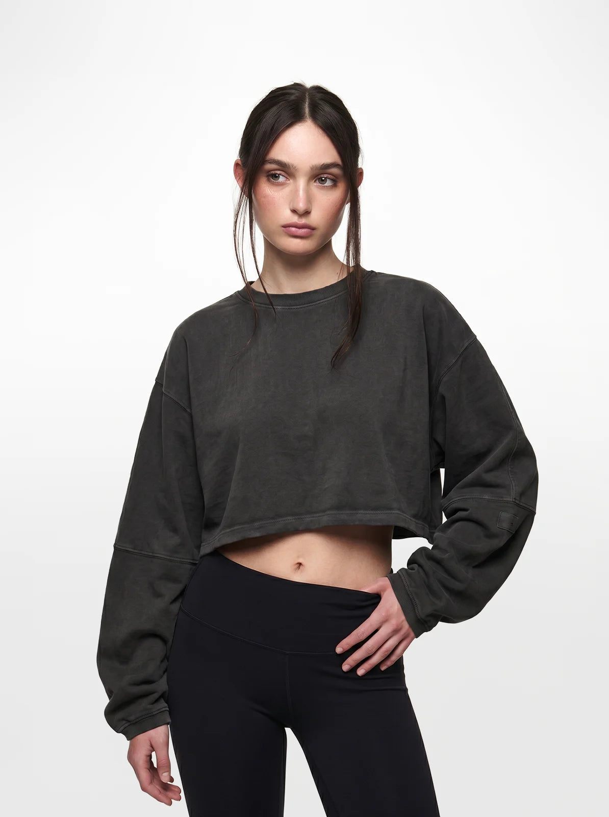 Woman wearing a black cropped t-shirt and leggings on a white background