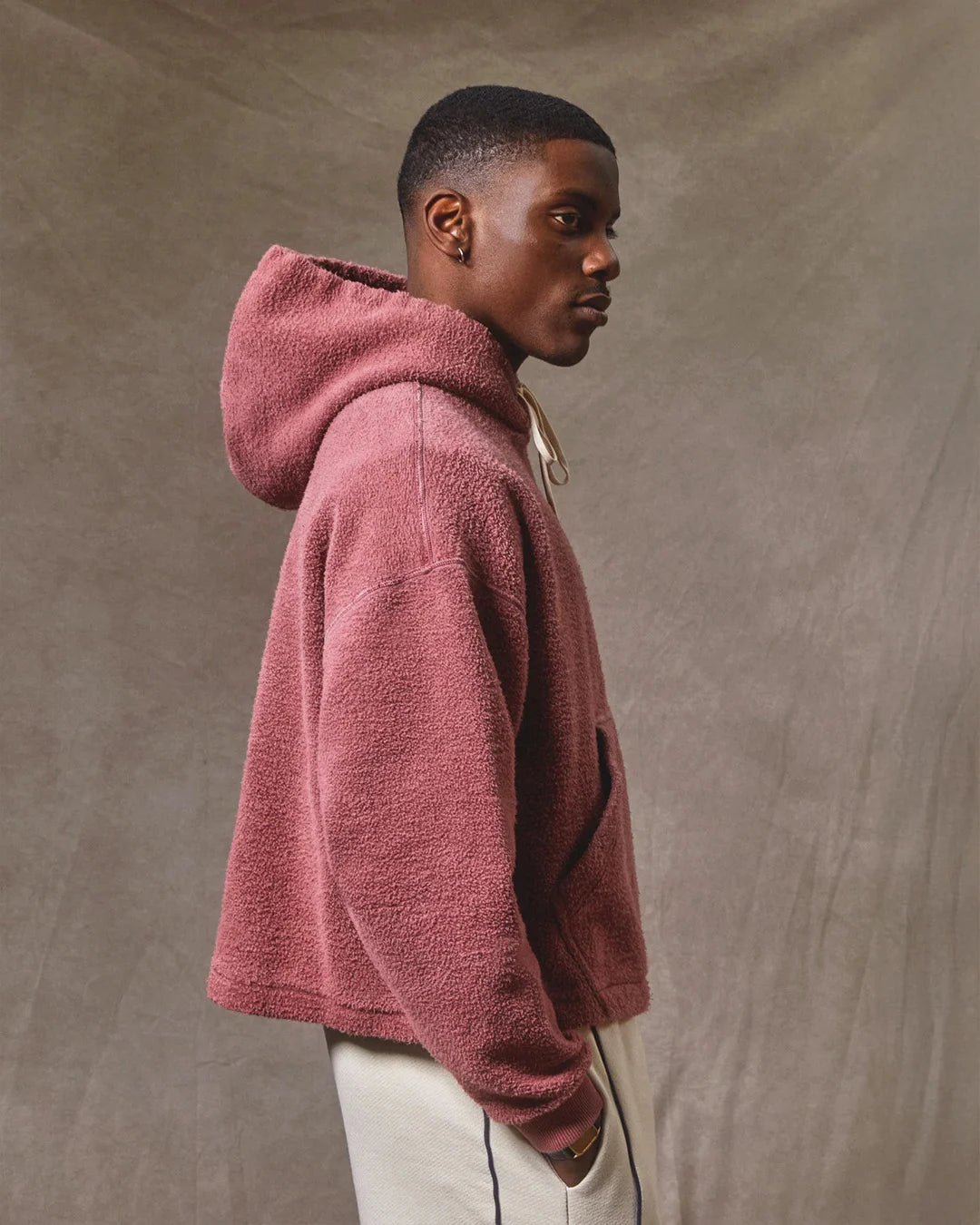 Person wearing a maroon hoodie against a beige background