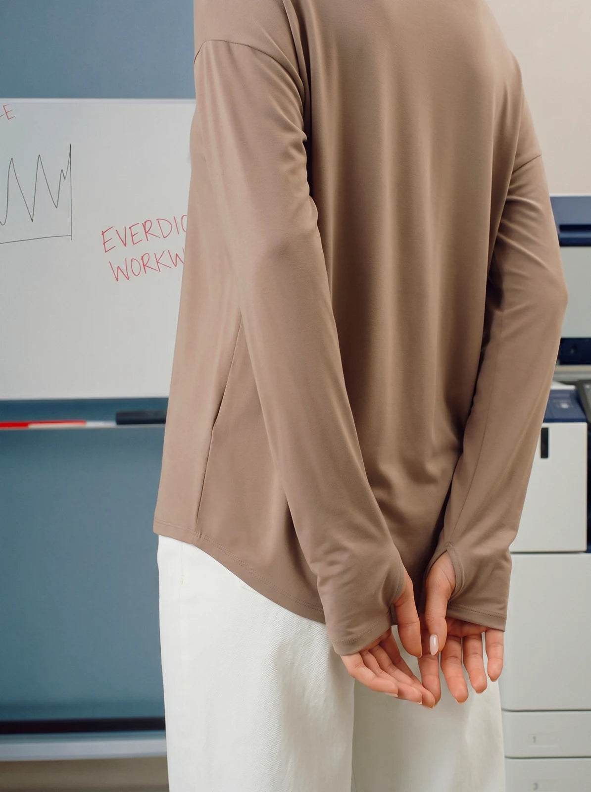 Person wearing a beige long-sleeve shirt in an office setting