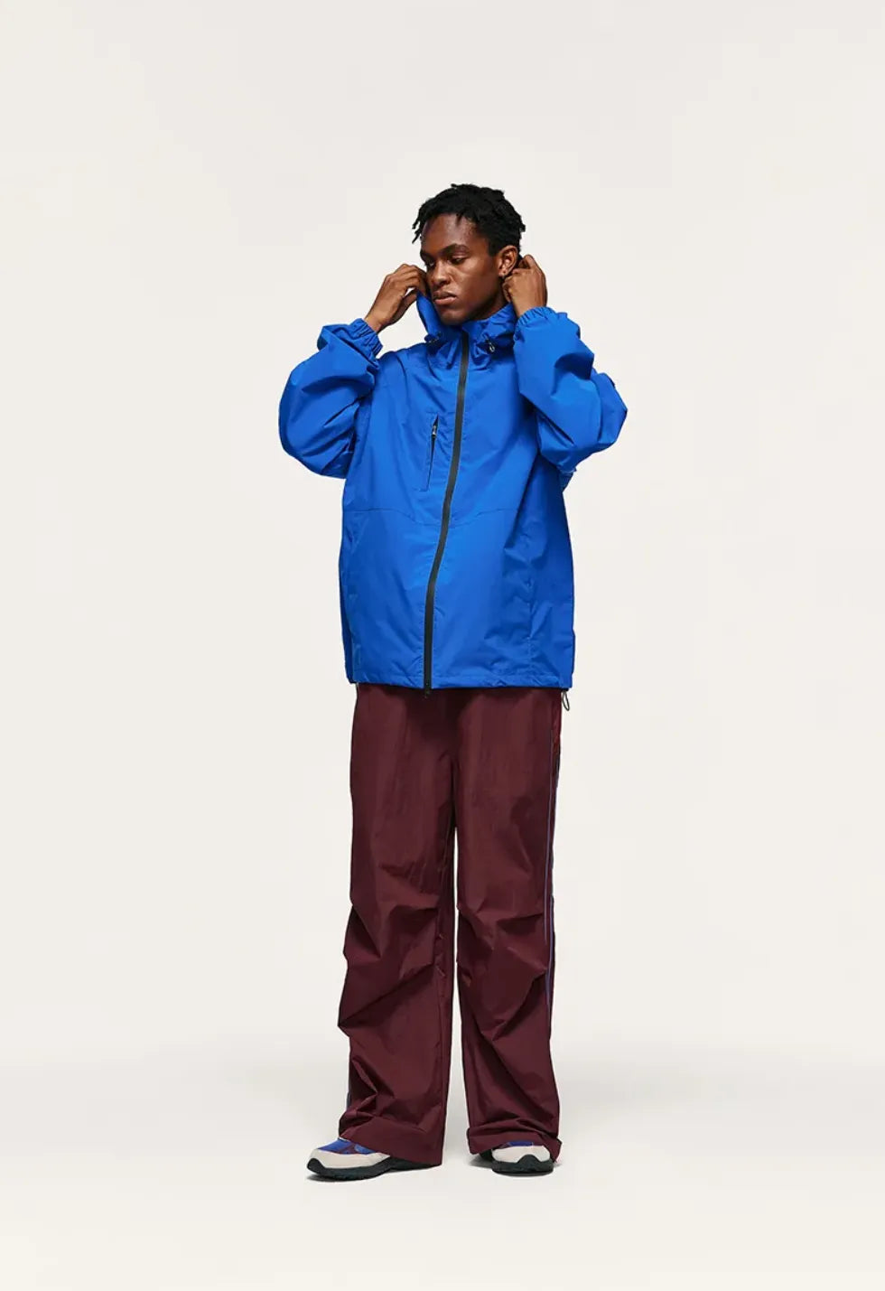 Person wearing a blue raincoat and maroon pants on a white background