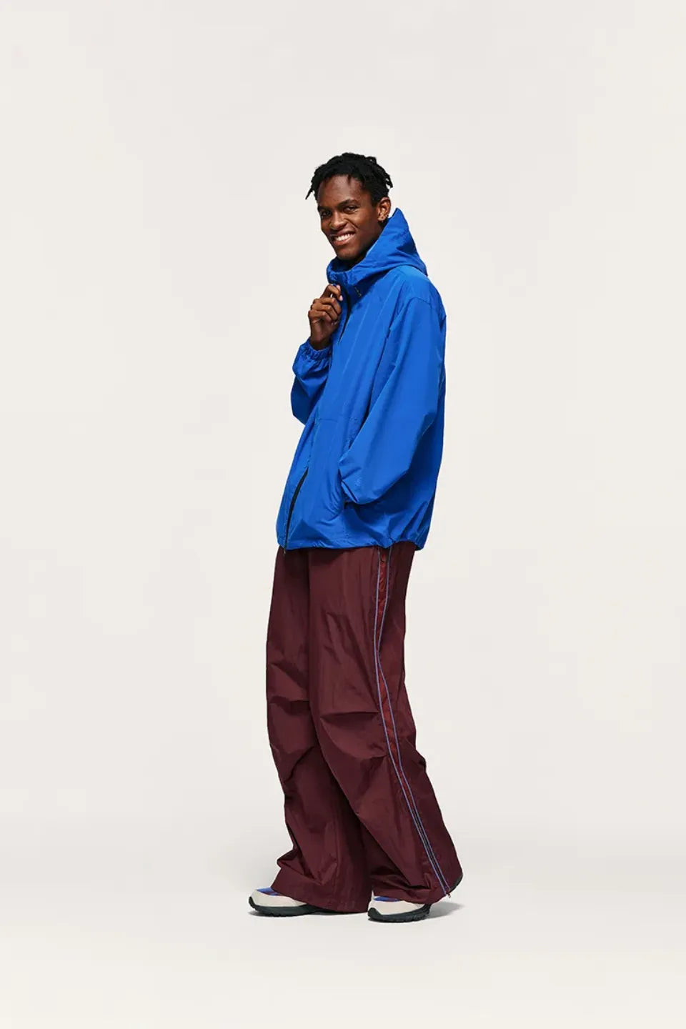 Person wearing a blue hoodie and maroon pants on a white background