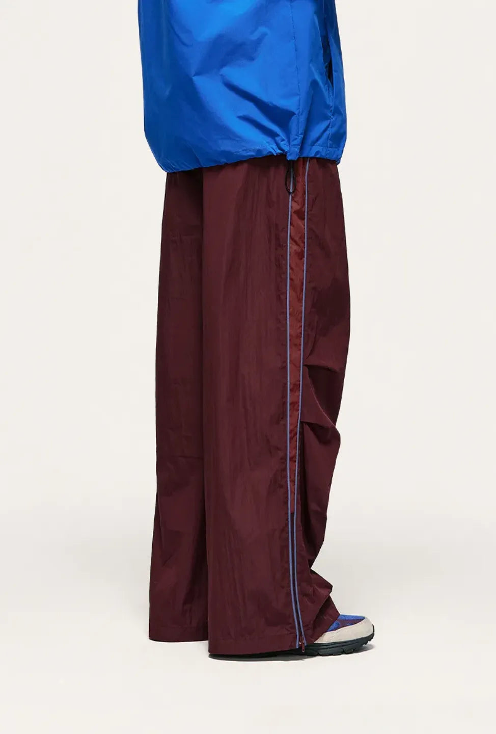 Person wearing a blue jacket and maroon pants on a white background